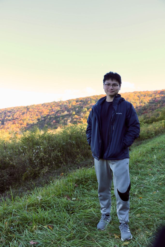 Rui Chen posing outside with fall foliage in the background.